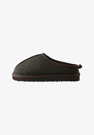 Zapatilla de lana gris con un patrón de espiga texturizado, puntera redondeada y suela de goma oscura. Cuenta con un ribete de tela y una lengüeta trasera para mayor facilidad.