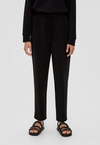 Zwarte taps toelopende sweatpants van zachte stof met een elastische tailleband met trekkoord, zijzakken en een gladde textuur.