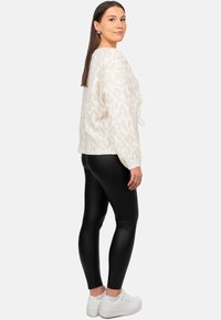Maglione a stampa leopardata crema con vestibilità ampia, cordino bianco, abbinato a leggings neri e sneakers bianche. Texture liscia e design confortevole.