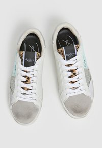 Sneakers bianchi con accenti metallici argento, fodera con stampa leopardata e un design testurizzato. Presentano lacci bianchi e logo sulla linguetta.