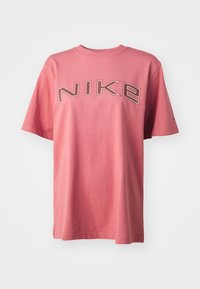 Pink cotton t-shirt featuring a large gray "NIKE" logo on the front, short sleeves, rounded neckline, and a relaxed fit.