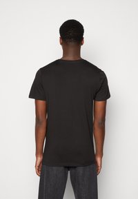 Camiseta negra de manga corta hecha de algodón. Presenta un cuello redondo clásico y una textura suave. Diseño simple sin patrones ni acentos adicionales.