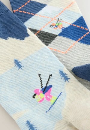 Strikkede sokker med et lyst blåt og hvidt design med et argyle mønster, kontrasterende blå accenter og et farverigt skiteamema.