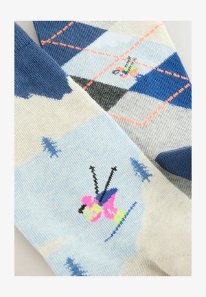 Strikkede sokker med et lyst blåt og hvidt design med et argyle mønster, kontrasterende blå accenter og et farverigt skiteamema.