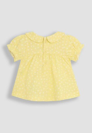 Kollane lühikeste varrukatega pluus, millel on Peter Pan krae, väikeste valgete lillemuster ning nööpidega selja kinnitamine. Pehme puuvillane kangas.