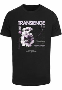 Melnā T-kreklā attēlots ziedu grafiks purpura un baltās krāsās, ar teksta elementiem dažādos fontus, radot slāņainu dizainu.