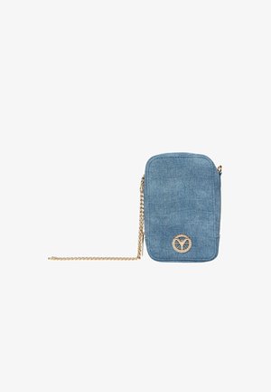 Kleine blauwe denim crossbodytas met afgeronde hoeken, gouden kettingriem en een cirkelvormige gouden logo-embleem in het midden aan de voorkant.
