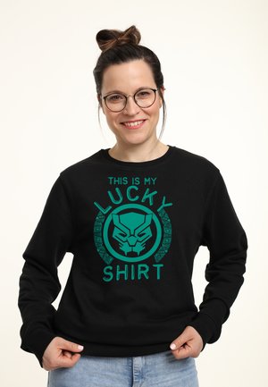 Černá mikina s zeleným textem a grafickým designem masky s nápisem "TOHLE JE MOJE ŠŤASTNÁ KOŠILE." Jednoduchý, ležérní střih.