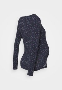 Blusa preta de manga longa com um pequeno padrão floral em roxo e azul, de corte ajustado, material suave e franzidos laterais para um ajuste de maternidade.