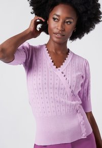 Lavendelstickad tröja med scalloped V-ringning, korta puffärmar, texturerade diamantmönster och ribbat avslut med knappprydnader.