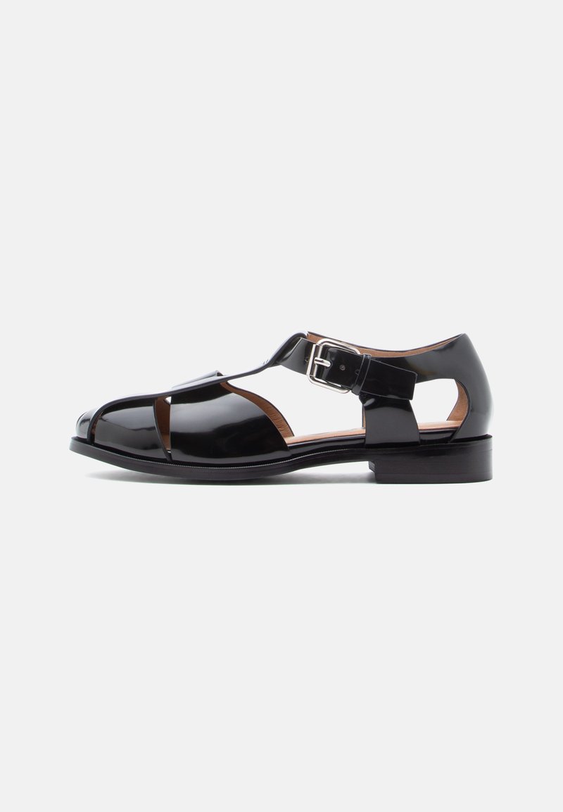 Sort sandal lavet af laklæder med udskæringsdesign, ankelrem med metalspænde og lav stabelhæle. Glat tekstur med blank finish.