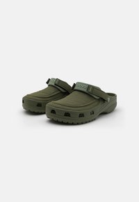 Sabots vert foncé avec une surface texturée et une sangle ajustable, dotés de trous de ventilation et d'une semelle épaisse à motif pour une meilleure adhérence.