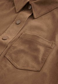 Bruine suède shirt met een gespreide kraag, knoopsluiting en een borstzak met een rechthoekige flap. Glad textuur met subtiele glans.