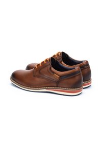 Zapatos de cuero marrón con punteras redondeadas, cordones naranjas en contraste, un detalle negro en el tacón y una suela blanca con una franja roja.