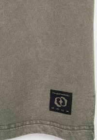 Bawełnowa koszulka w oliwkowym kolorze, z prostokątną czarną metką z nazwą marki i logo. Gładka faktura i prosty design.