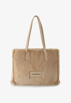 Beige Einkaufstasche aus Kunstpelz mit braunen Ledergriffen, rechteckige Form, sichtbare Naht, und einem auffälligen Valentino-Logo-Patch.