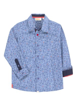 Chemise à manches longues bleue avec de petits triangles blancs, noirs et rouges, poignets contrastants bleu foncé et boutons rouges et bleus.