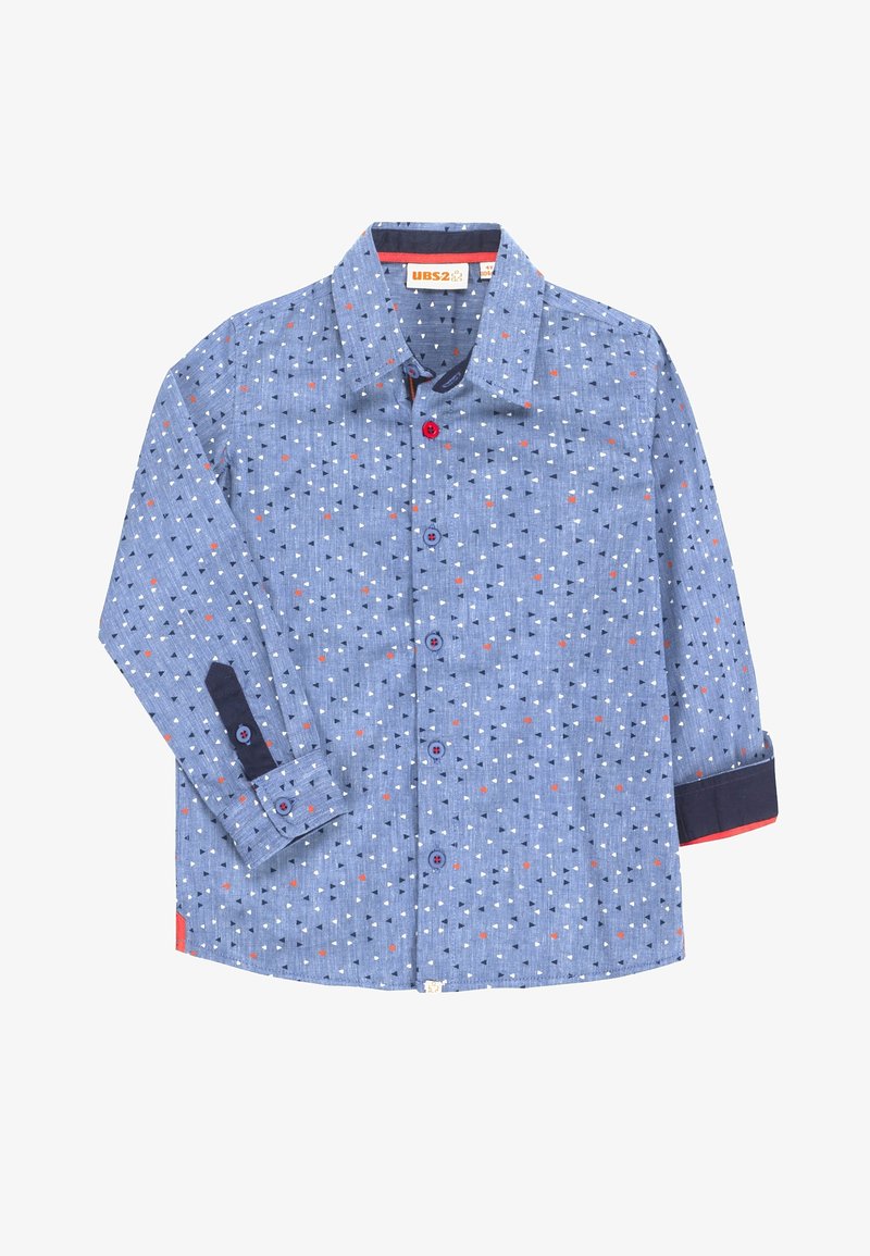 Camisa azul de manga larga abotonada con pequeños triángulos blancos, negros y rojos, puños en azul oscuro contrastantes y botones rojos y azules.