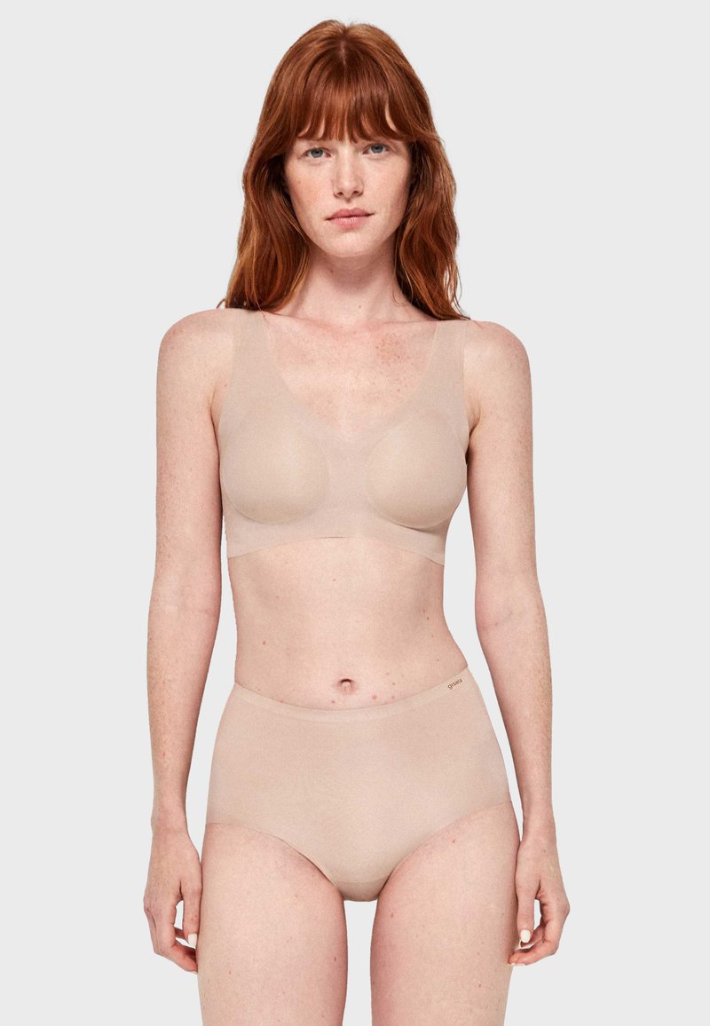 Soutien-gorge couleur nude et culotte taille haute en matériau lisse et extensible. Présente des larges bretelles et une construction sans coutures.