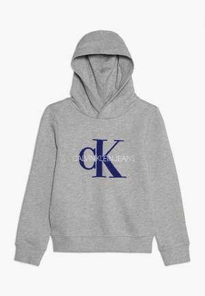 Jasnoszara bluza z kapturem z niebieskim logo „cK” i białym napisem „Calvin Klein Jeans” na przodzie, ze ściągaczami przy mankietach i na dole.