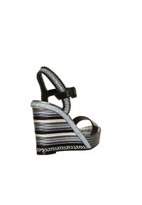 Sandalia cuña negra y plateada con una correa texturizada. Presenta rayas horizontales y una suela trenzada. Incluye una correa ajustable en el tobillo.