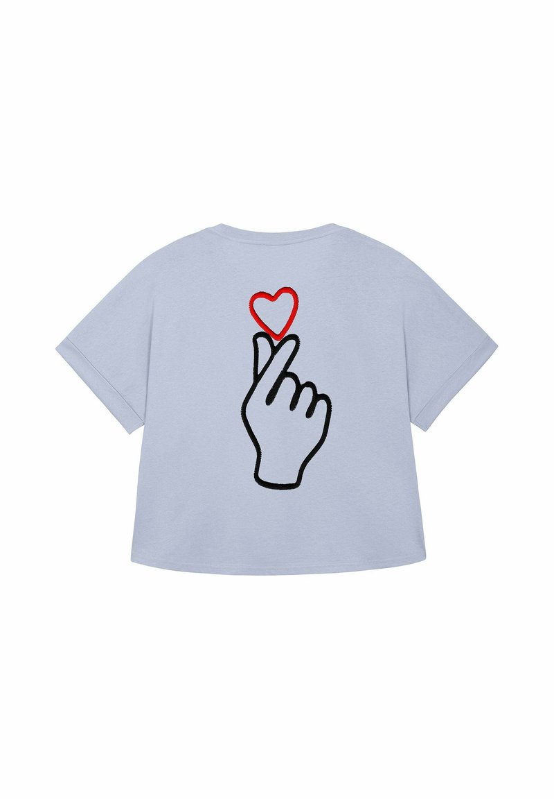 T-shirt bleu clair présentant un graphisme d'une main faisant un geste de "cœur avec les doigts" au-dessus d'un cœur rouge. Design décontracté et ludique.
