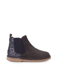 Bota Chelsea de ante negra con panel trasero brillante, fuelle elástico en los lados, tirador y suela de goma marrón.