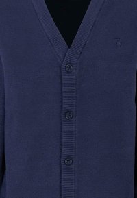 Cardigan blu navy realizzato in morbido tessuto a maglia, con scollo a V, cinque bottoni e bordi a costine lungo il collo e la parte anteriore.