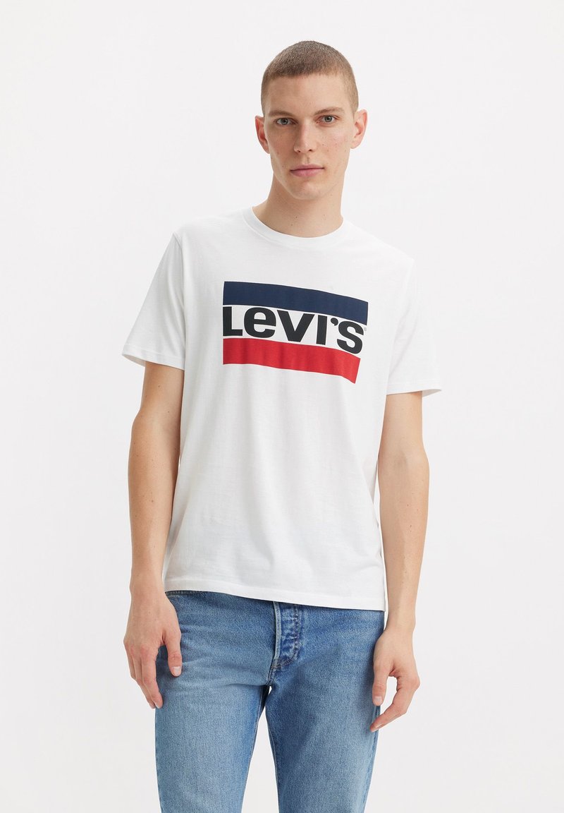 Witte katoenen t-shirt met een merkgraphic in blauw en rood op een rechthoekige achtergrond. Korte mouwen en een ronde hals.