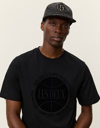 Čierne tričko s krátkym rukávom s textúrovaným okrúhlym logom so "LES DEUX" v strede. Šedá kockovaná čiapka s vyšívanými "LD" na prednej strane.