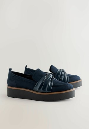 Navy-blaue Wildlederschuhe mit einem glänzenden, geknoteten Akzent aus Lackleder an der Vorderseite und einer dicken schwarzen Plateausohle.