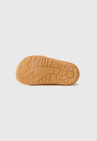 Talpă din cauciuc de culoare marron deschis, cu un model de textură pentru aderență, având un logo vizibil și diferite designuri de suprafață pentru tracțiune.