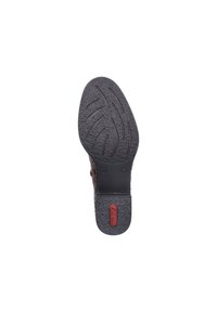 Semelle de chaussure en caoutchouc noir avec surface texturée et design de bande de roulement motif. Présente un logo rouge sur la section du talon, affichant sa durabilité.