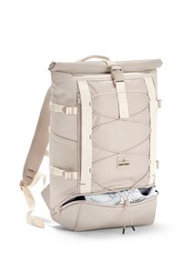 Beige színű, lehajtható hátizsák textúrált felülettel, elülső fűződíszítéssel, oldalsó zsebekkel és cipők tárolására alkalmas cipzáras alsó rekesszel.