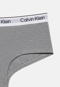 Γκρι βαμβακερά εσώρουχα με λευκή ελαστική μέση που φέρει μαύρη επιγραφή "Calvin Klein", παρουσιασμένα σε λευκό φόντο.