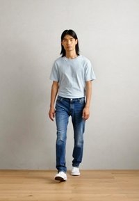 Lyseblå bomull T-skjorte, klassisk passform, kombinert med medium vask denim jeans. Hvite joggesko fullfører det uformelle antrekket. Glatt, minimal tekstur.