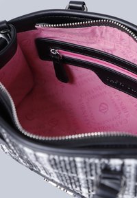Borsa intrecciata bianca e nera con zip aperta che mostra un interno in tessuto rosa e una piccola tasca con zipper all'interno.