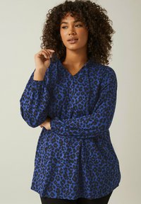 Blå leopardmönstrad blus med V-ringning, långa puffärmar och elastiska manschetter; har en lös passform och lätt tygtextur.