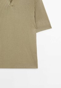 Pull beige en maille côtelée à manches courtes avec col en V et manches retroussées sur fond blanc.