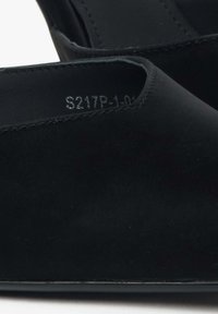 Czarne zamszowe buty wsuwane charakteryzujące się eleganckim designem, zaokrąglonym noskiem i minimalną ilością szwów, z widoczną metką rozmiarową wewnątrz.