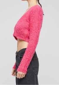 Rosa fluffig kort ärmad tröja med långa ärmar, med en djup V-ringning och texturerad, mjuk finish. Kombineras med svarta högmidjade byxor.