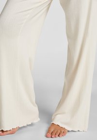 Crème-kleurige brede broek gemaakt van een gestructureerde stof, met verticale ribbels en een geschulpte zoom.
