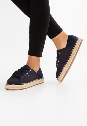 Námořnické espadrilky s plátěným svrškem, šněrovacím designem a lanovým podešví. Obsahují kontrastní textilní akcenty a malou detailní logo.