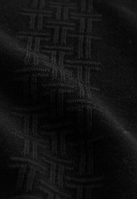 Sort stof med et struktureret vævet mønster. Blød, glat tekstur med fremhævede søm i et gitterlayout henover overfladen.