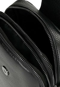 Černá texturovaná kožená taška se dvěma otevřenými zipovými přihrádkami a přední klopou se zavíráním na magnetický patent.