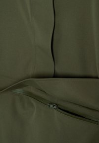 Olijfgroene stof met een deels open horizontale rits die de binnenvoering onthult, met zichtbare stiksel-details op glad textiel.