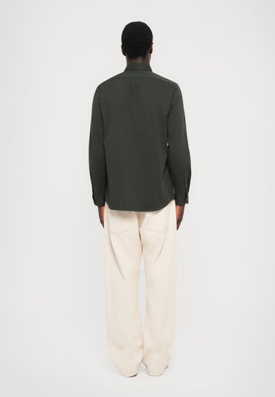 Mørkegrønn, langermet skjorte med knapper på mansjettene; lett stoff; kombinert med off-white, løstsittende bukser med baklommer.