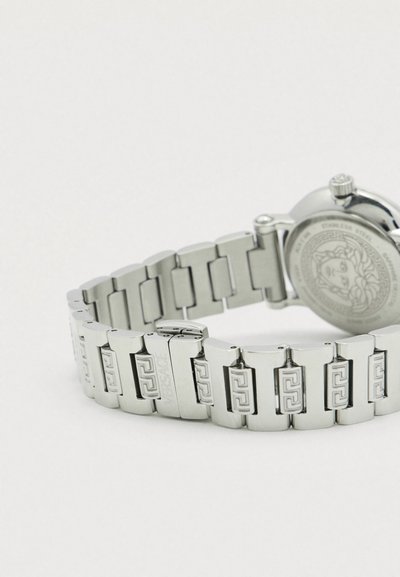 Srebrny zegarek ze stali nierdzewnej z bransoletą z ogniw, zdobiony grawerowanymi wzorami i okrągłą kopertą z teksturowanym tyłem.