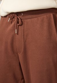 Bruna sweatpants med elastisk midja och dragsko, sidofickor och ett mjukt, texturerat tyg.