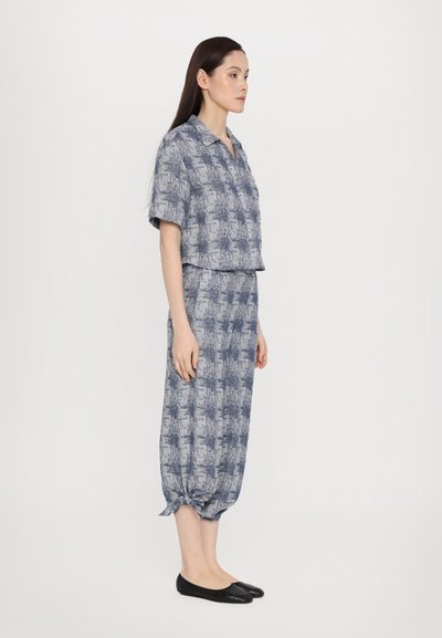 Tvådelad outfit i blått, bestående av en boxig topp med kort ärm och en lång, lös kjol med knutdetalj vid fållen. Texturerat rutmönster.